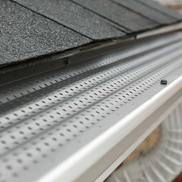 a white gutter with holes in it is sitting on top of a roof .